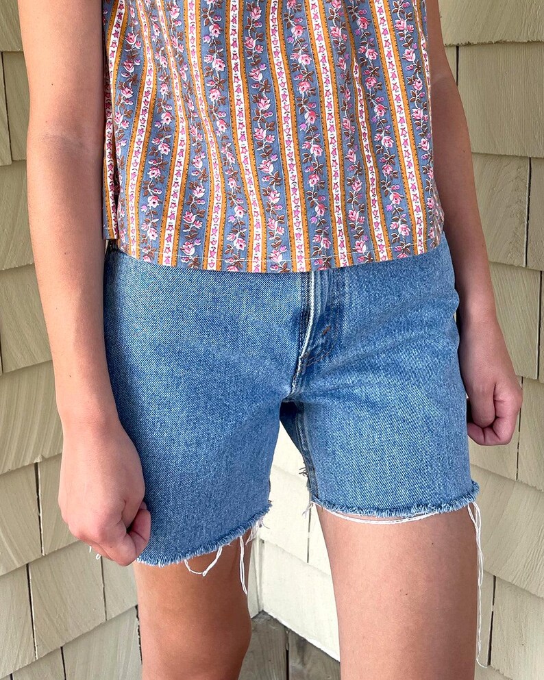 K&ouml;nnte beinhalten: Eine hellblaue Jeans-Shorts mit ausgefranstem Saum. Die Shorts haben einen hohen Bund und eine lockere Passform.
