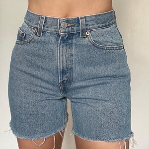 K&ouml;nnte beinhalten: Hellblaue Jeans-Shorts mit ausgefranstem Saum. Die Shorts haben eine hohe Taille und f&uuml;nf Taschen.