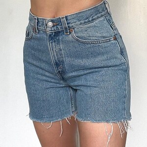 K&ouml;nnte beinhalten: Hellblaue Jeans-Shorts mit ausgefranstem Saum. Die Shorts haben eine hohe Taille und f&uuml;nf Taschen.