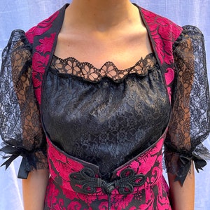 May include: A black lace top with a red and pink floral pattern. The top has a lace overlay and a sweetheart neckline.