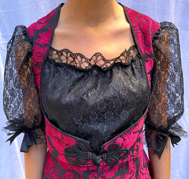 May include: A black lace top with a red and pink floral pattern. The top has a lace overlay and a sweetheart neckline.