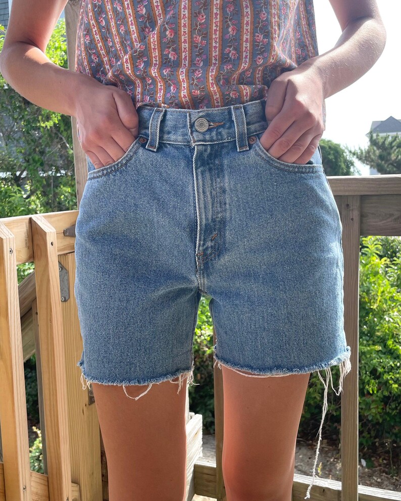 K&ouml;nnte beinhalten: Eine hellblaue Jeans-Shorts mit ausgefranstem Saum. Die Shorts haben einen hohen Bund und sind aus einem weichen, bequemen Stoff.