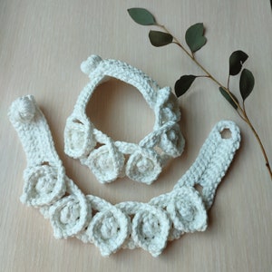 May include: A set of two white crocheted necklaces with a floral design. The necklaces are made of white yarn and have a delicate, feminine look.