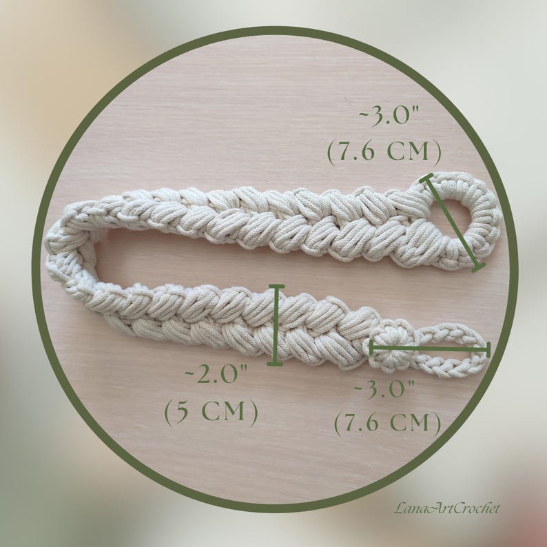 May include: A white cotton rope macrame cord with a braided design. The cord is 2 inches wide and 3 inches long. The cord is measured in inches and centimeters.