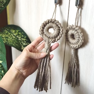 Pode incluir: Dois tapetes de macramé bege com franjas. Cada tapete apresenta um design circular com um círculo menor no centro.