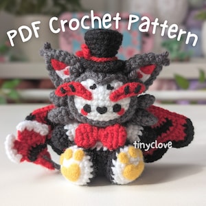 May include: A crocheted plush toy in the shape of a wolf-like creature, featuring a top hat and bow tie. The toy is primarily gray, white, black, and red, with yellow paw pads. The text "PDF Crochet Pattern" is at the top.