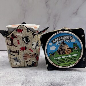 May include: Two fabric cozies for ice cream containers. One features a dog pattern on a beige background, the other is black with paw prints. A Ben & Jerry's ice cream container is visible.