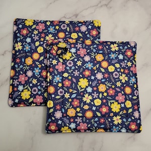 Op de afbeelding: Twee blauwe en witte pottenlapjes met een geel, roze en groen bloemenpatroon.
