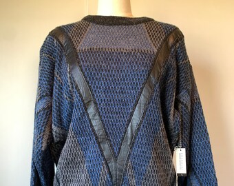May include: A blue and gray patterned sweater with black leather accents. The sweater has a V-shaped design on the front and a ribbed hem.