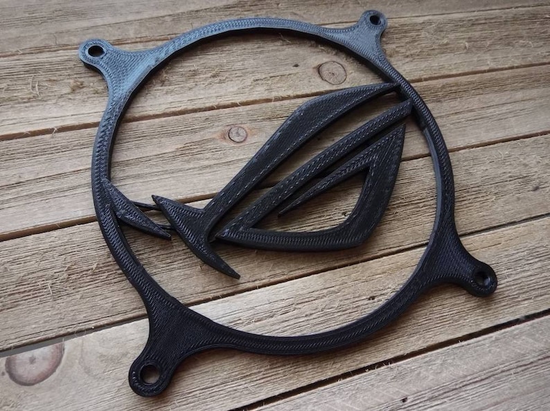 May include: A black plastic fan grill with a 3D printed ASUS ROG logo. The logo is a stylized eye with wings.