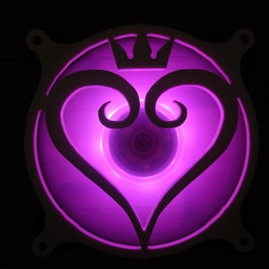 Op de afbeelding: Een witte plastic computerventilator met een paars licht dat schijnt door een uitsparing in de vorm van een hart met een kroon erop.