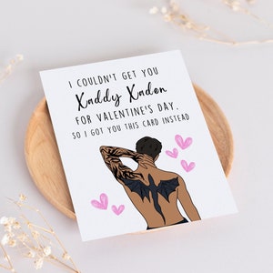 May include: A white card with black text that reads "I couldn't get you Xaddy Xaden for Valentine's Day. So I got you this card instead."  The card features a cartoon illustration of a man with a black dragon tattoo on his back.