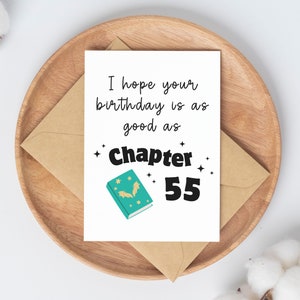 May include: A white card with a green book and gold stars. The text on the card reads "I hope your birthday is as good as Chapter 55".