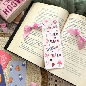 Puede incluir: Un marcap&aacute;ginas rosa y blanco con el texto "I think I like this little life" en rosa y blanco. El marcap&aacute;ginas tiene un fondo a cuadros rosa y blanco con una mariposa rosa, una fresa rosa y una copa de vino rosa con un lazo rosa.