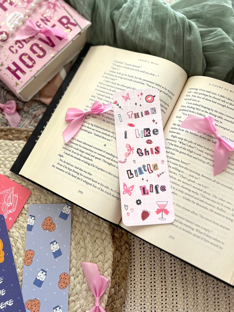 Puede incluir: Un marcap&aacute;ginas rosa y blanco con el texto "I think I like this little life" en rosa y blanco. El marcap&aacute;ginas tiene un fondo a cuadros rosa y blanco con una mariposa rosa, una fresa rosa y una copa de vino rosa con un lazo rosa.