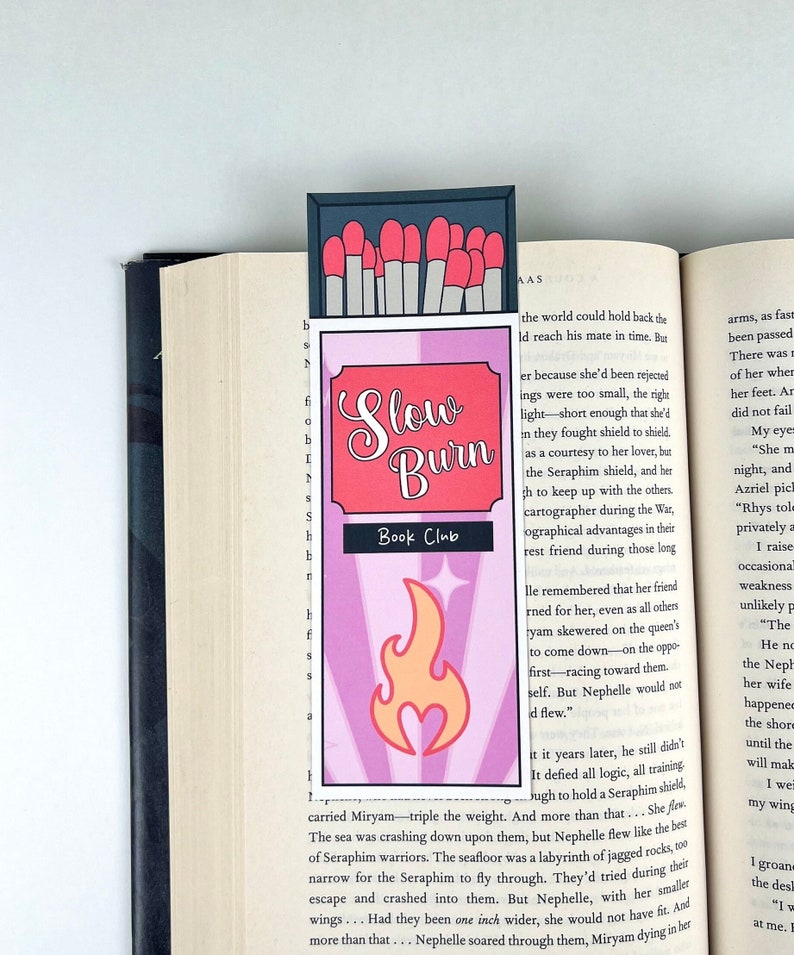 Puede incluir: Un marcap&aacute;ginas rosa y morado con un dise&ntilde;o de cerillas. El marcap&aacute;ginas presenta el texto "Slow Burn Book Club" y una llama estilizada con un coraz&oacute;n en la parte inferior.