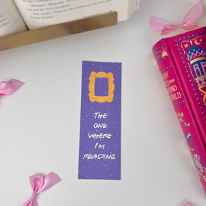 May include: Purple bookmark with a white outline of the iconic "Friends" apartment door frame and the text "The One Where I'm Reading".