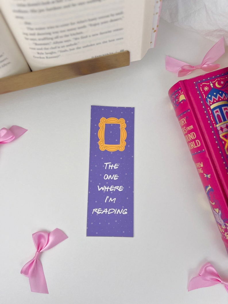 May include: Purple bookmark with a white outline of the iconic "Friends" apartment door frame and the text "The One Where I'm Reading".