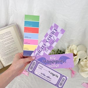 May include: A set of four purple and white bookmarks with a fantasy theme. The bookmarks feature text that reads "Night Court Obsessed", "Big Wingspan Energy", and "Velaris Illyrian Airlines".