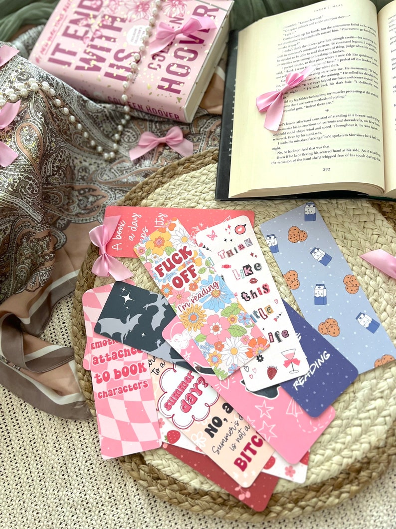 Puede incluir: Una colecci&oacute;n de marcadores coloridos con varios dise&ntilde;os y textos. Algunos de los marcadores presentan patrones de cuadros rosa y blanco, dise&ntilde;os florales y textos como "Think Like This" y "Summer Day?" Otros presentan una silueta negra de un murci&eacute;lago, un patr&oacute;n de cuadros rosa y blanco y textos como "Emotionally Attached to Book Characters" y "No, a Summer's Day is not a Bitch".