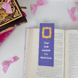 May include: Purple bookmark with a white outline of the iconic "Friends" show frame. The bookmark has white stars and the text "The One Where I'm Reading" in white.