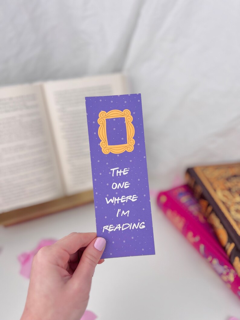 May include: Purple bookmark with a yellow frame and the text "THE ONE WHERE I'M READING".