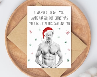 May include: A humorous Christmas card featuring a man wearing a Santa hat and a black and white illustration of a shirtless man. The text on the card reads "I wanted to get you Jamie Fraser for Christmas but I got you this card instead."