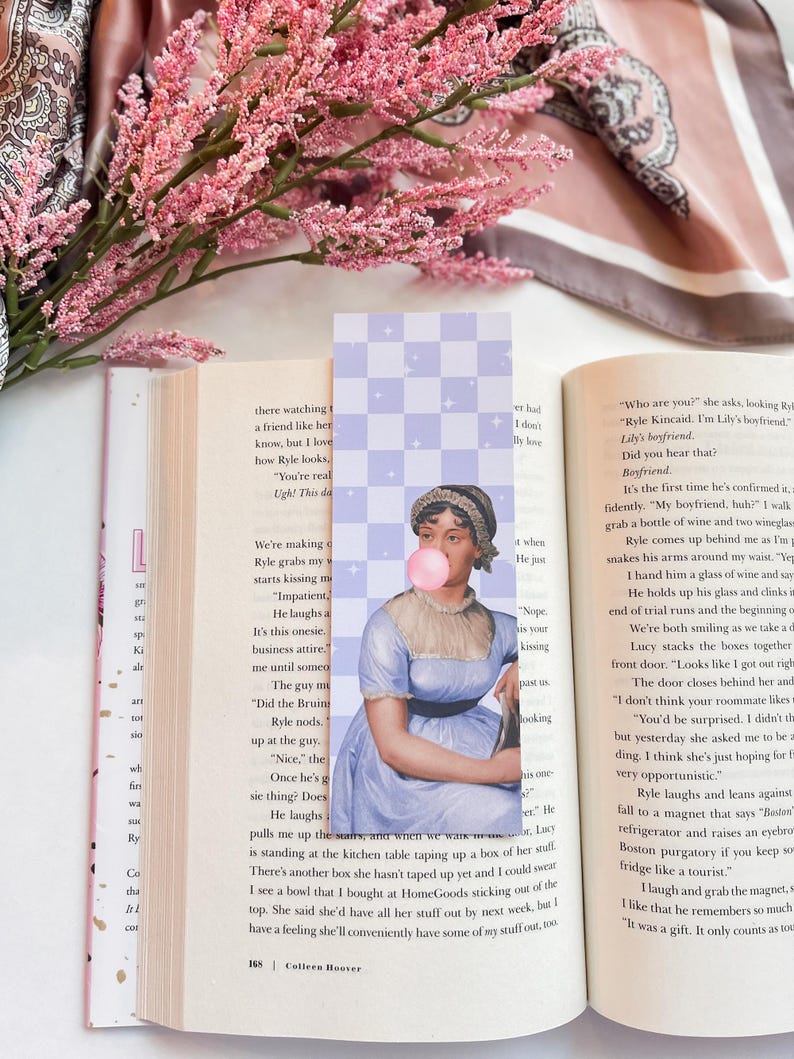 May include: A book bookmark featuring a portrait of a woman blowing a bubble. The bookmark is printed on a light purple background with a checkered pattern. The text "You're really ugh! This day" is visible on the page behind the bookmark.