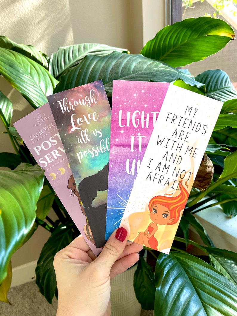 Puede incluir: Cuatro marcap&aacute;ginas coloridos con citas inspiradoras. Los marcap&aacute;ginas presentan un fondo de galaxia con acentos de brillo. Las citas son "Through Love all is possible", "Light it Up", "My Friends are with me and I am not afraid", y "Crescent Post Serv".