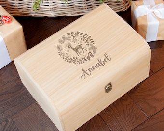 May include: A light wood keepsake box with a hinged lid and a brass latch. The box is engraved with a reindeer in a wreath of holly and the name "Annabel".