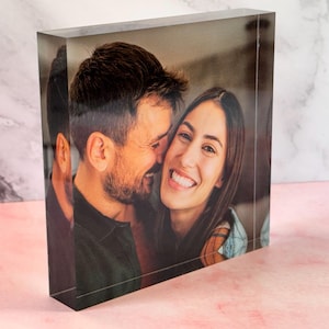 May include: A close-up photo of a couple smiling at each other. The man is on the left and the woman is on the right. They are both looking at the camera.