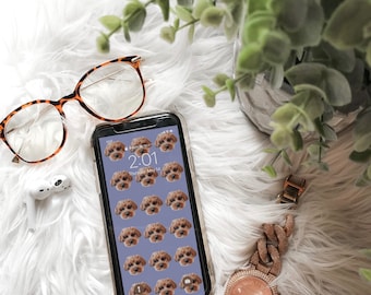 May include: A smartphone with a purple background and a grid of images of a brown dog's face. The phone is on a white fluffy surface with a pair of tortoiseshell glasses and a gold watch with a chain link band.