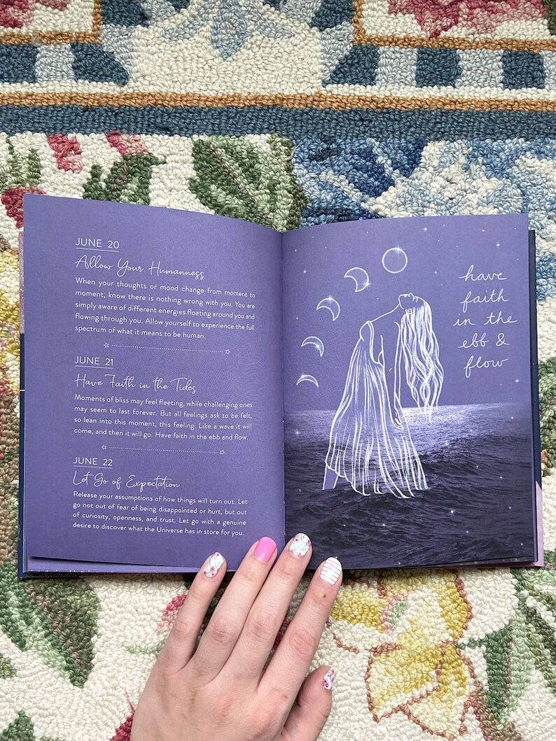 May include: An open book with a purple cover, featuring text and illustrations. The left page has text about June 20, 21, and 22. The right page has a drawing of a person with long hair, the moon, and the text "have faith in the ebb & flow."