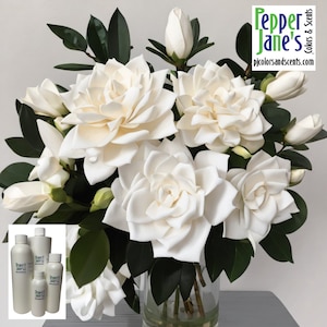 May include: A bouquet of white gardenias in a clear glass vase with green leaves. The vase is sitting on a gray surface. The image also includes four bottles of essential oil with the text "Pepper Jane's Colors & Scents" on the label.