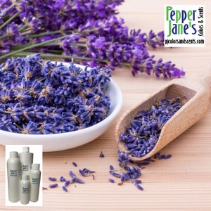 May include: A close-up of lavender buds in a white bowl and a wooden scoop, with sprigs of lavender in the background. The image also shows several bottles with the text "Pepper Jane's Colors & Scents" and the website address.