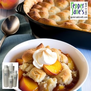 May include: A bowl of peach cobbler topped with whipped cream and a sprinkle of cinnamon. The image also shows a baking dish of cobbler and several bottles with the text "Pepper Jane's Colors & Scents".