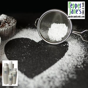 May include: A close-up shot features a cupcake dusted with powdered sugar, a heart-shaped design made with sugar, and a metal sieve filled with sugar. The image also includes several white bottles with the text "Pepper Jane's Colors & Scents".