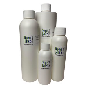 May include: A collection of white plastic bottles with white screw-on caps. Each bottle has a label with the text "Pepper Jane's" in green and the website address. The bottles vary in size, suggesting different product volumes.