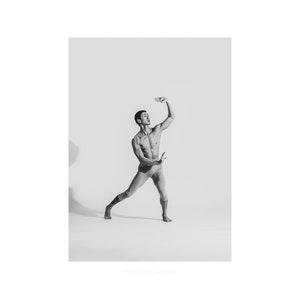 Peut inclure: Une photo en noir et blanc d'une personne dans une pose de danse. La personne porte un caleçon noir et est debout sur une jambe, l'autre jambe étant tendue derrière elle. Les bras de la personne sont levés au-dessus de sa tête.