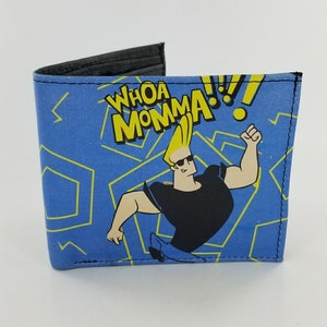 Könnte beinhalten: Eine blaue und gelbe Brieftasche mit einer Comicfigur darauf. Die Figur trägt eine Sonnenbrille und ein schwarzes Shirt. Der Text "WHOA MOMMA!" ist auf der Brieftasche aufgedruckt.