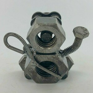 May include: A whimsical sculpture of a snowman made from metal nuts and bolts. The snowman has a long, thin arm made from a metal rod and a small, round head.