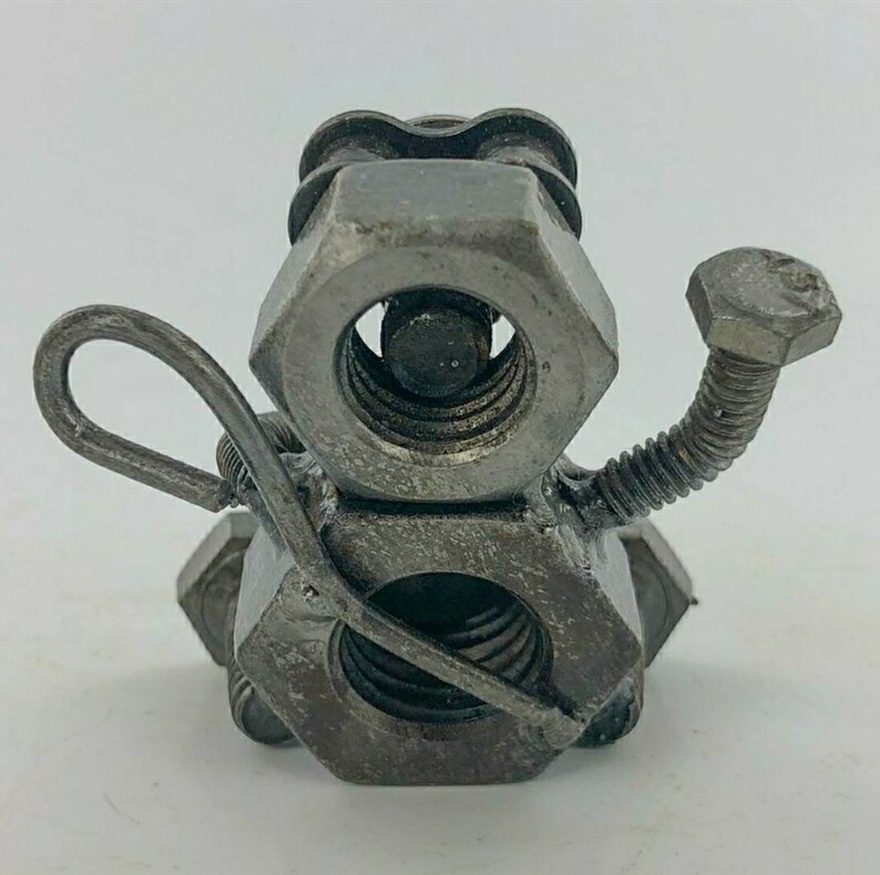 May include: A whimsical sculpture of a snowman made from metal nuts and bolts. The snowman has a long, thin arm made from a metal rod and a small, round head.