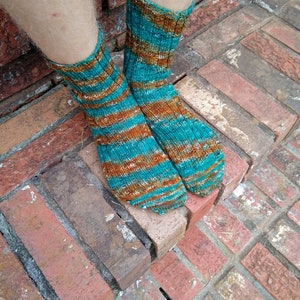 May include: A pair of teal and brown striped socks with a white background. The socks are knitted and have a textured look.