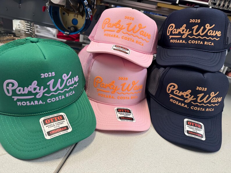Op de afbeelding: Een collectie van vijf truckerpetten in groen, roze en marineblauw. Elke pet is voorzien van de geborduurde tekst 2025 Party Wave Nosara, Costa Rica. De petten hebben een mesh achterkant, een schuimrubberen voorkant en een Otto-sticker op de klep.