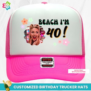 May include: A white and pink trucker hat with a photo frame and the text "Beach I'm 40!" in a retro font. The hat has a pink mesh back and a white front with a pink brim. The hat is customizable with a photo.