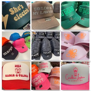 Op de afbeelding: Een collectie trucker-petten met schuimrubberen voorzijde in diverse kleuren zoals zwart, bruin, groen, roze, oranje, blauw en wit, voorzien van diverse aangepaste zeefdrukteksten en grafische ontwerpen zoals bijen, lantaarns en slogans.