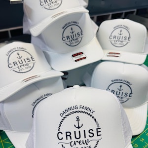 May include: A collection of white trucker hats with a mesh back and a curved brim. Each hat features a circular design with an anchor, the words "CRUISE CREW", and the year "EST. 2025" or "EST. 2021". The hats are branded with "MABESA FAMILY" and "DANNUG FAMILY".