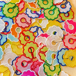May include: A collection of circular, scalloped-edge clothing rack dividers made of white mesh fabric. Each divider features a slit for attachment and is finished with a vibrant embroidered border in colors including yellow, pink, green, and blue.