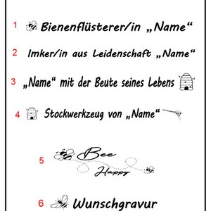 May include: A white rectangular sign with black text and illustrations. The text includes phrases like "Bee Happy" and "Wunschgravur". The sign also features a logo and the words "GRAVURTECHNIK GESCHENKBEDARF". The theme appears to be related to bees and beekeeping.