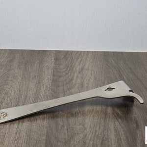 May include: A stainless steel beekeeping hive tool with a curved end, a hook, and a hole. The tool has a flat, elongated body with a logo on the handle. The tool is designed for hive maintenance.